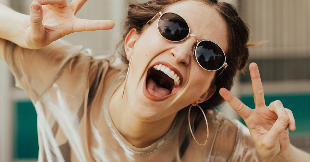 selective focus photography of jolly woman using peace hand gesture